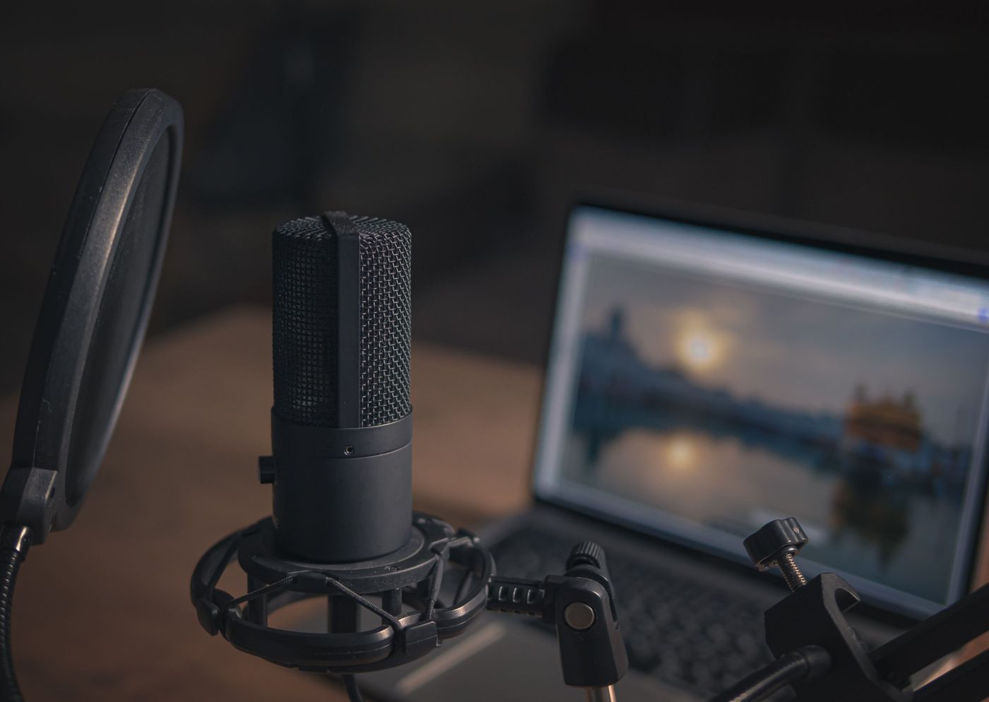 A condenser microphone with a pop filter beside a laptop