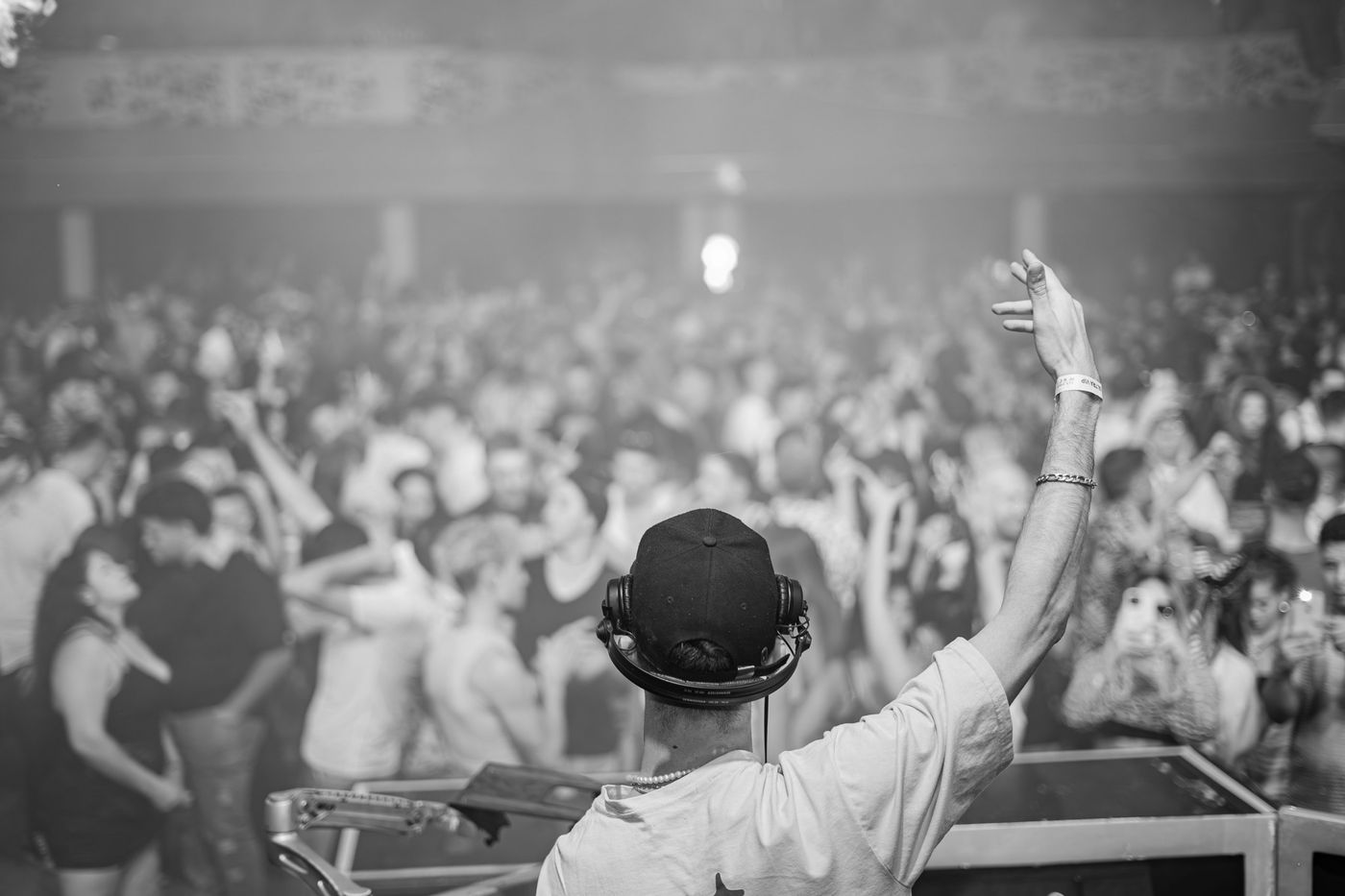 A DJ raising an arm to a packed dance floor
