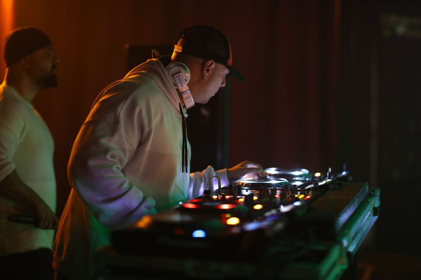 A DJ leaning over the decks in a dimly lit club
