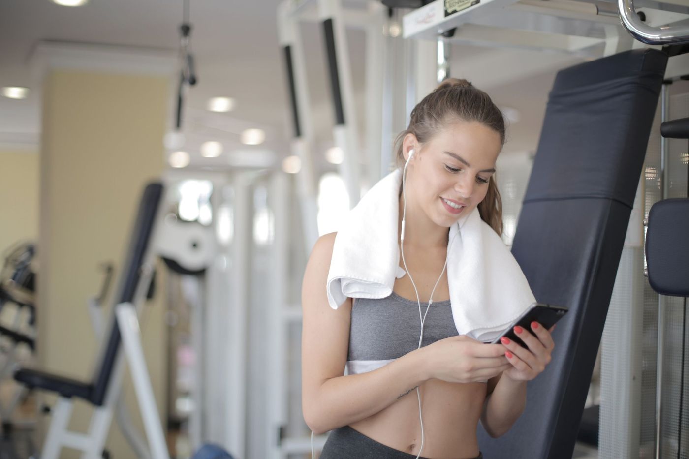 A woman checking her phone with earphones in at the gym