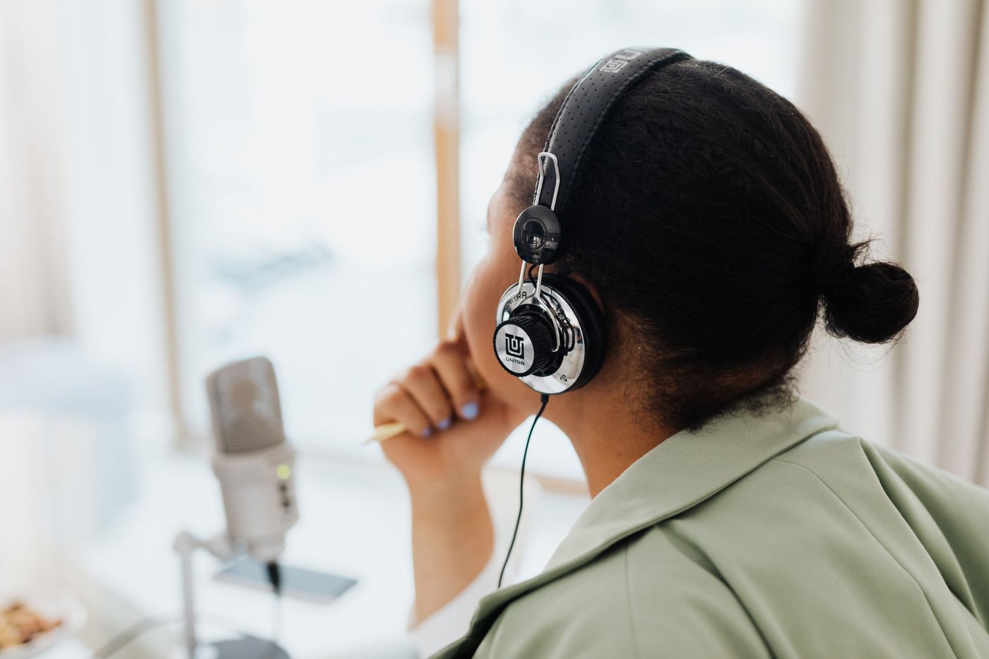 A listener in headphones beside a studio microphone
