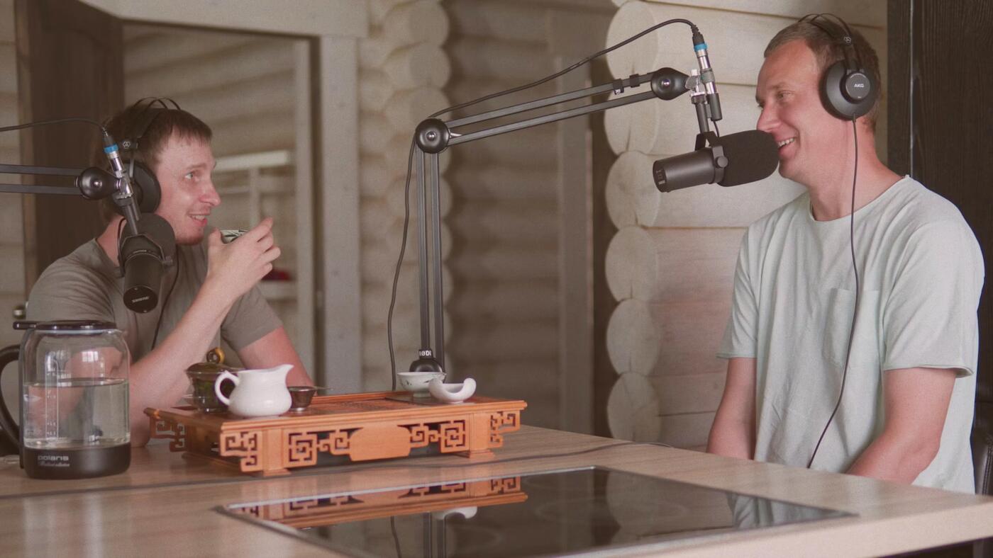Two friends laughing at their microphones in a podcast studio