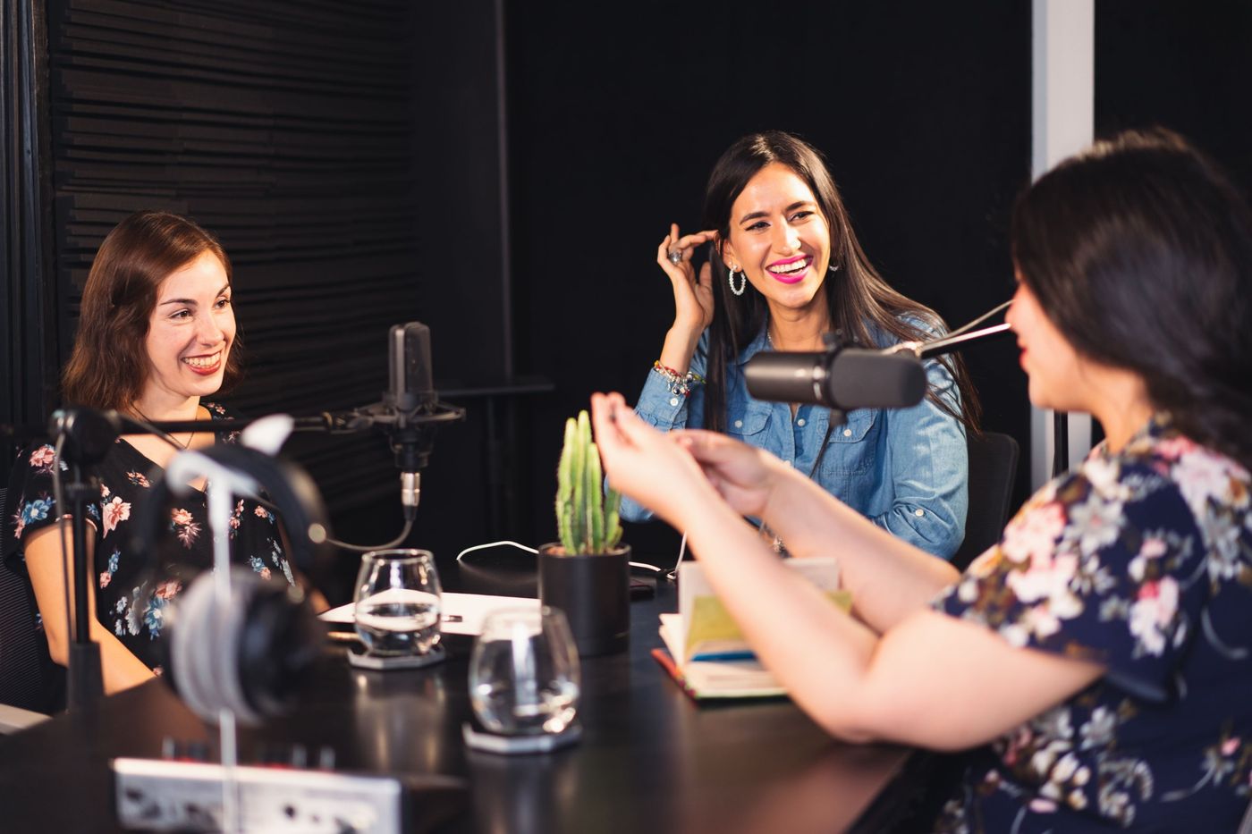 Three presenters laughing together around studio microphones